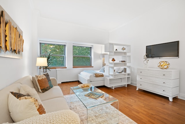bedroom with ornamental molding and wood finished floors