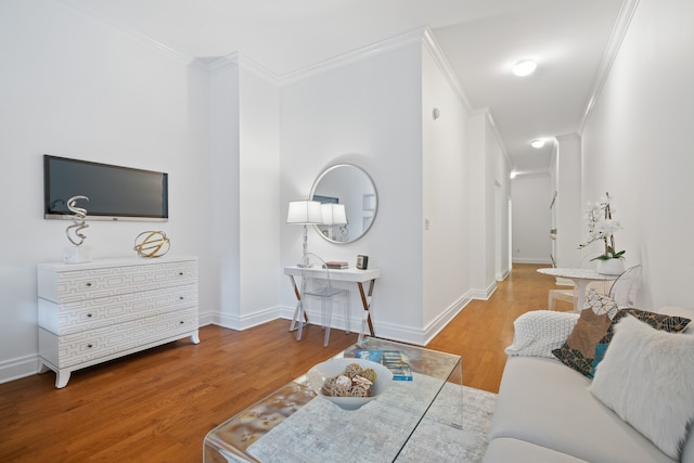 living area with crown molding, baseboards, and wood finished floors
