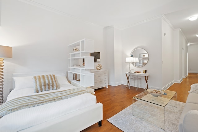 bedroom with baseboards, ornamental molding, and wood finished floors