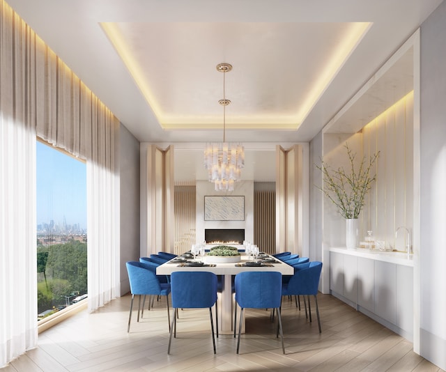 dining area featuring a lit fireplace, a tray ceiling, wood finished floors, and a chandelier