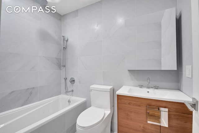 bathroom featuring vanity, tiled shower / bath combo, toilet, and tile walls