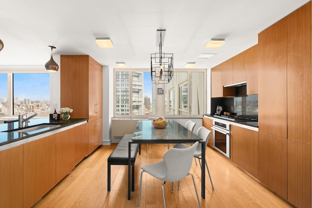 kitchen featuring appliances with stainless steel finishes, plenty of natural light, light wood-type flooring, and a chandelier