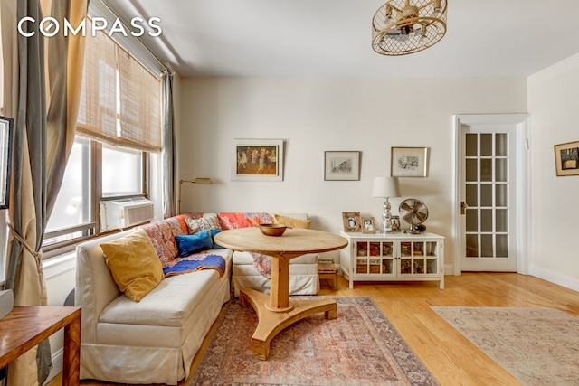 sitting room with baseboards, wood finished floors, and cooling unit