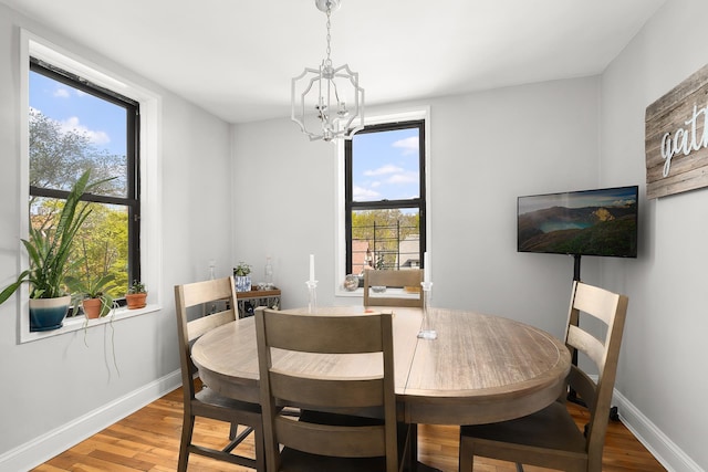 dining space featuring baseboards, an inviting chandelier, and wood finished floors