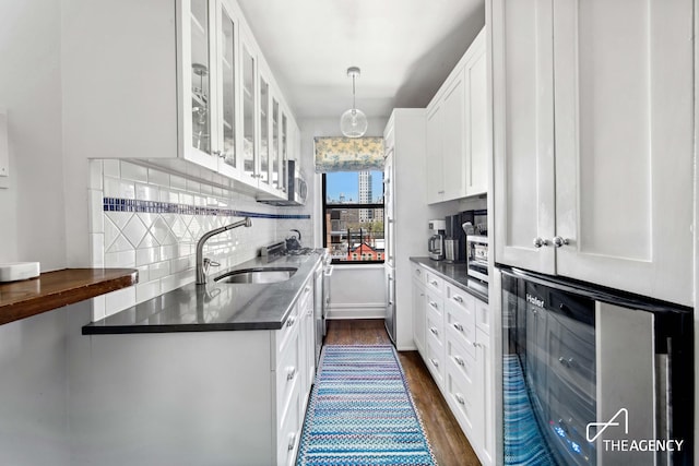 kitchen featuring white cabinets, glass insert cabinets, a sink, and dark wood-type flooring