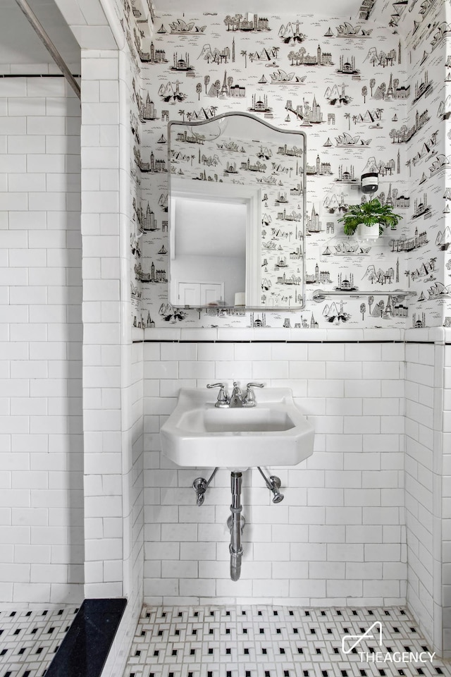 full bathroom featuring wallpapered walls and a tile shower