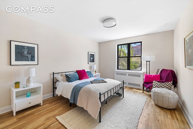 bedroom featuring radiator, baseboards, and light wood-type flooring