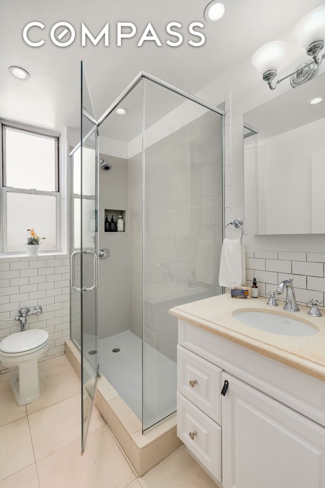 bathroom with tile patterned flooring, vanity, toilet, tile walls, and a stall shower
