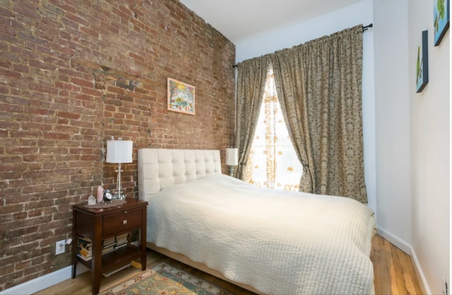 304 W 88th St Unit 1D, New York City, NY 10024 - bedroom featuring baseboards, wood finished floors, and brick wall