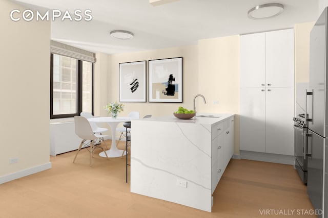 interior space with baseboards, a sink, and light wood-type flooring