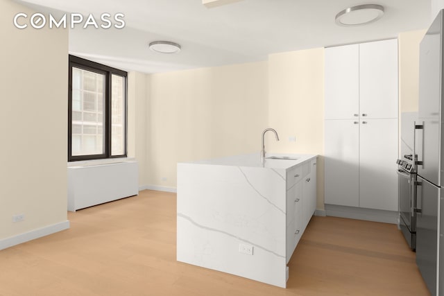 kitchen with a sink, light stone counters, baseboards, white cabinets, and a peninsula