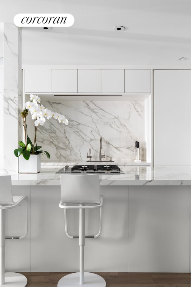 kitchen featuring white cabinetry, light stone countertops, modern cabinets, and wood finished floors
