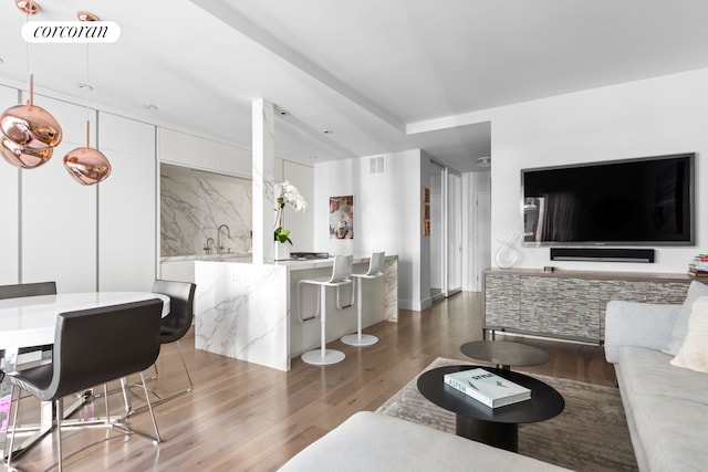 living area with baseboards, wood finished floors, and visible vents