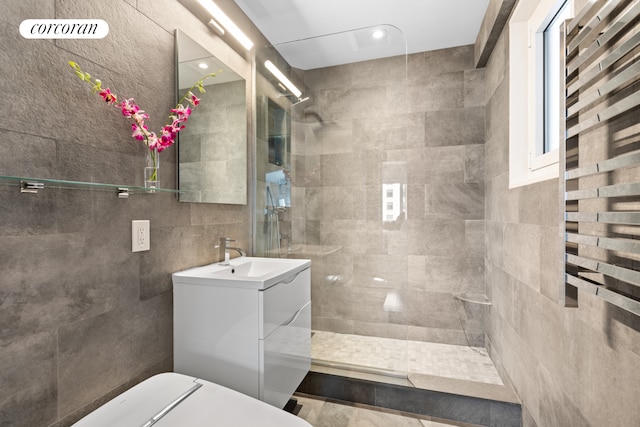 bathroom with a walk in shower, vanity, and tile walls