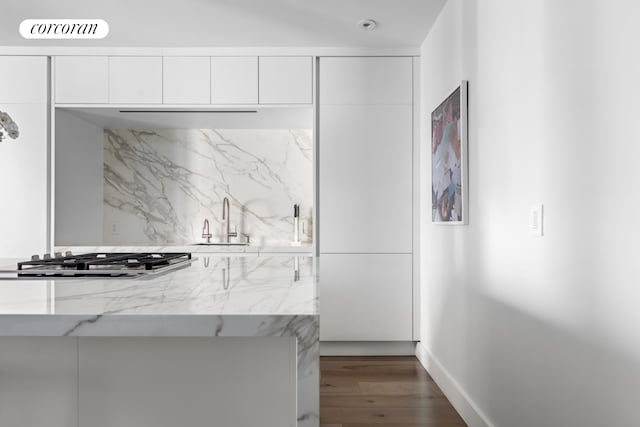 kitchen with modern cabinets, stainless steel gas cooktop, a sink, white cabinets, and dark wood-style floors
