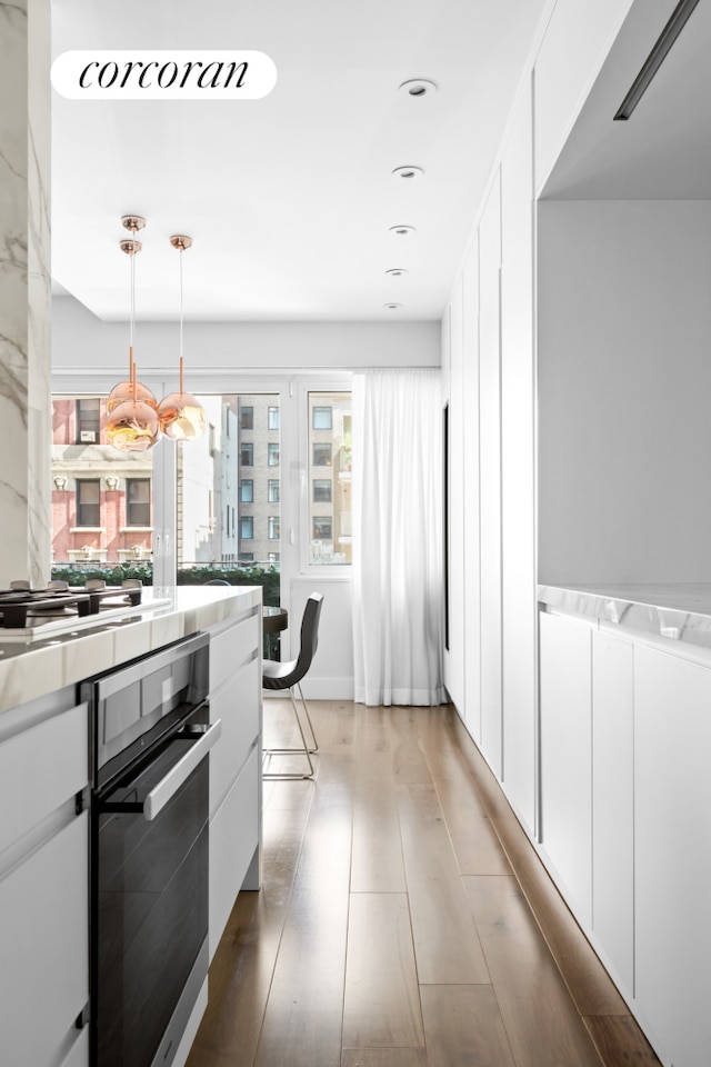 kitchen with light countertops, hanging light fixtures, white cabinets, and oven