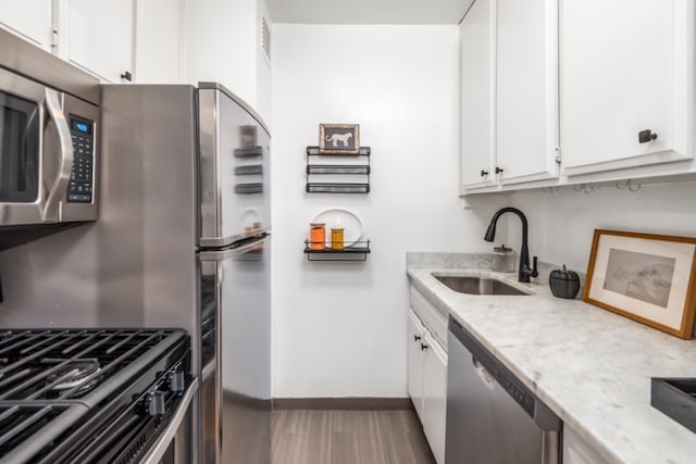 77 7th Ave Unit 7Kk, New York City, NY 10011 - kitchen featuring appliances with stainless steel finishes, a sink, white cabinetry, baseboards, and light stone counters