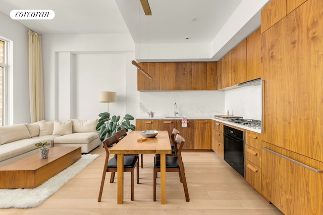 kitchen with modern cabinets, a sink, light wood finished floors, stainless steel gas stovetop, and oven