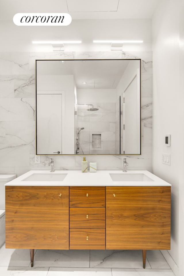 bathroom featuring double vanity, a sink, and a marble finish shower