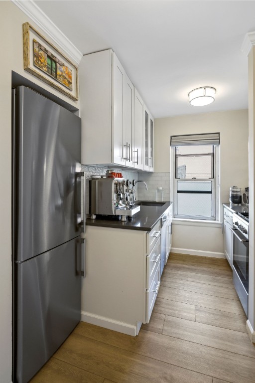 kitchen featuring a sink, appliances with stainless steel finishes, light wood finished floors, and white cabinetry