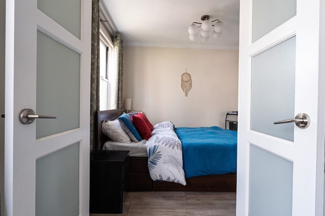 bedroom featuring ornamental molding and wood finished floors