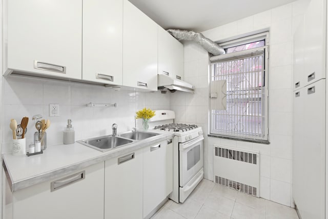 kitchen with radiator heating unit, white gas stove, light countertops, under cabinet range hood, and a sink