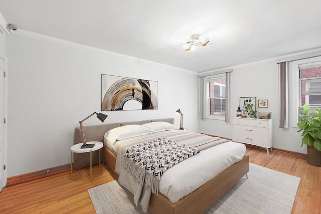 bedroom with crown molding, baseboards, and light wood finished floors