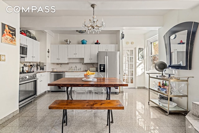 kitchen with stainless steel appliances, granite tiled floors, a sink, and white cabinetry