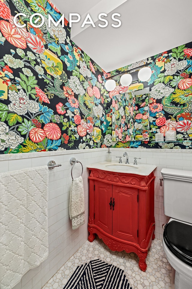 2166 Broadway Unit 4C, New York City, NY 10024 - bathroom with tile walls, toilet, tile patterned floors, wainscoting, and vanity