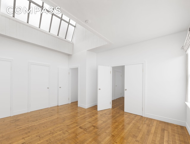 23 W 12th St, New York City, NY 10011 - unfurnished bedroom with two closets, light wood-style floors, and a towering ceiling