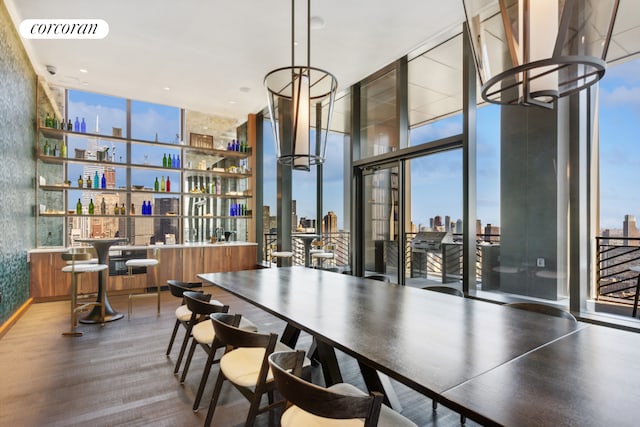 dining area with a wall of windows, a view of skyline, a community bar, and a chandelier