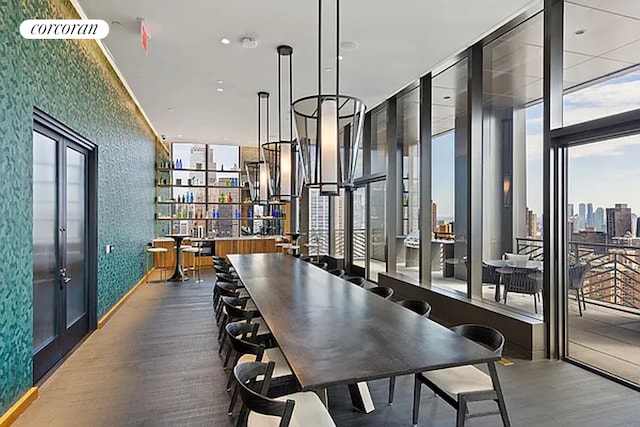 dining space featuring wallpapered walls, healthy amount of natural light, wood finished floors, and expansive windows