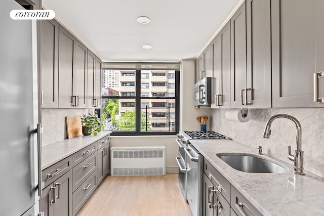 kitchen with radiator heating unit, a sink, gray cabinetry, stainless steel appliances, and recessed lighting