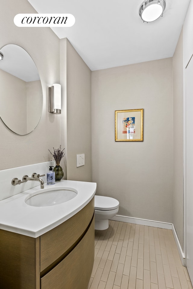 bathroom with toilet, vanity, and baseboards