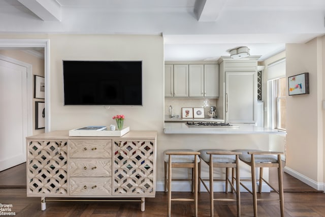 kitchen with a kitchen bar, gas stovetop, light countertops, and a sink