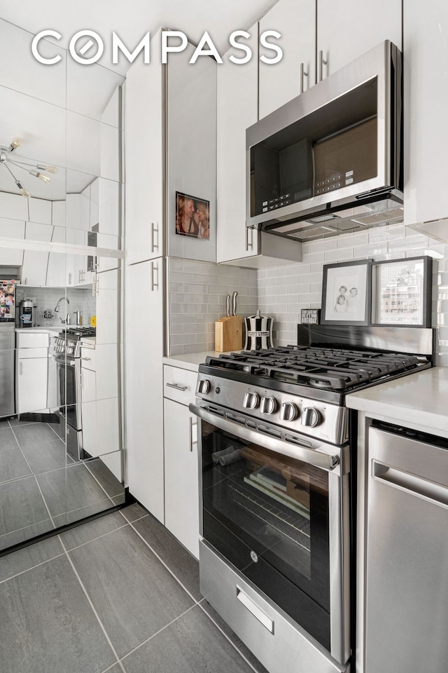 kitchen with appliances with stainless steel finishes, white cabinetry, tasteful backsplash, and light countertops