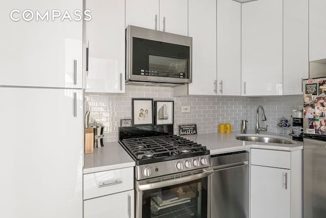 kitchen featuring stainless steel appliances, a sink, light countertops, and white cabinets