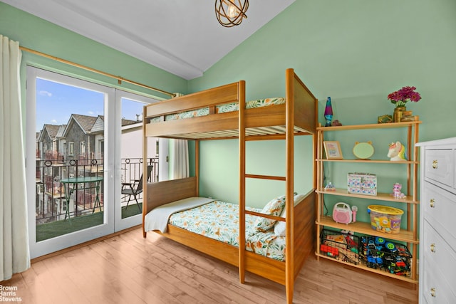 bedroom with access to outside, wood-type flooring, and vaulted ceiling