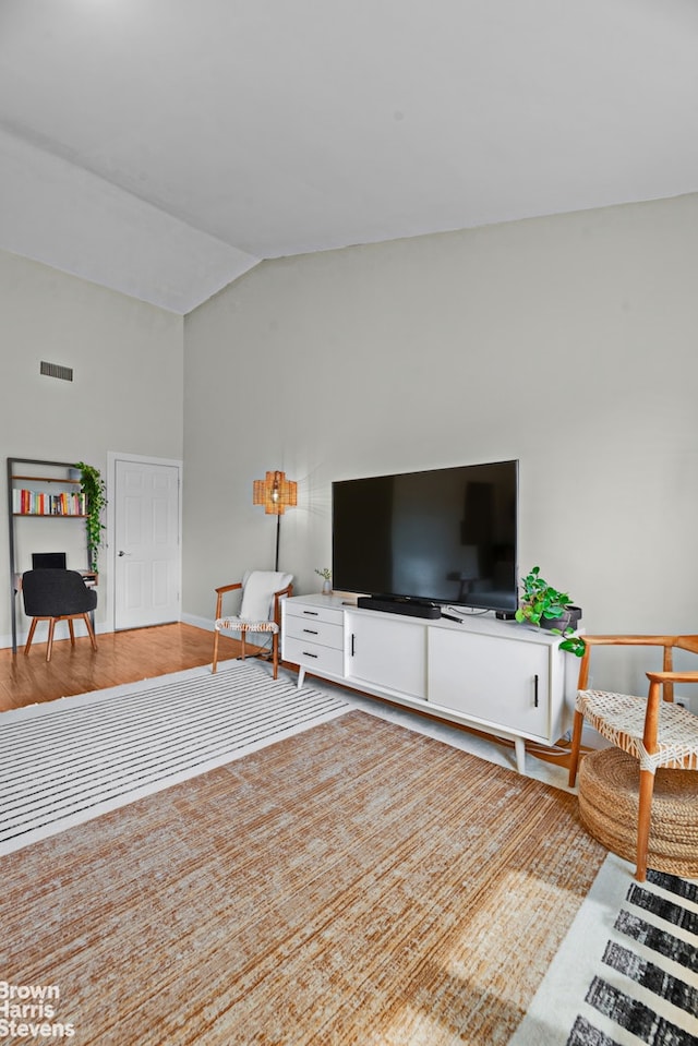 living area with lofted ceiling, baseboards, and wood finished floors