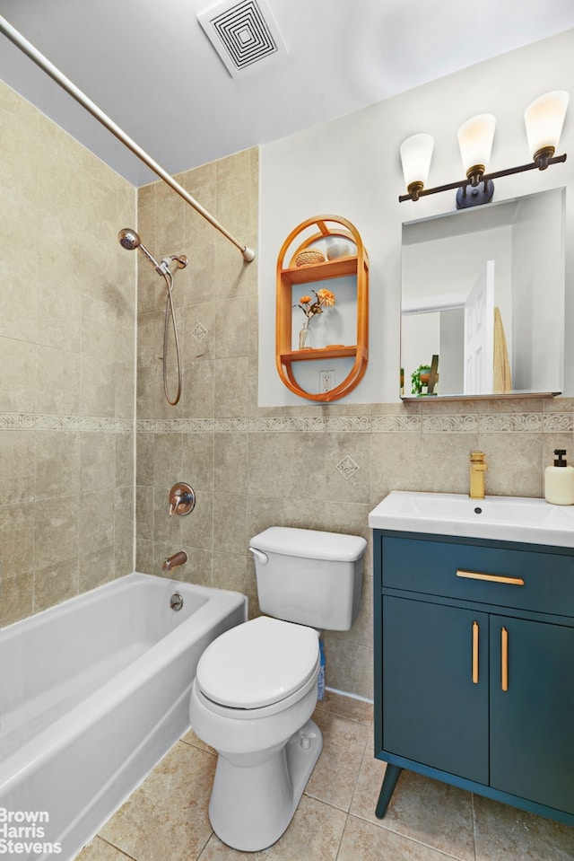 bathroom featuring tile patterned floors, tile walls, toilet, vanity, and shower / tub combination
