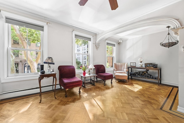 living area with healthy amount of natural light, a ceiling fan, baseboard heating, and arched walkways