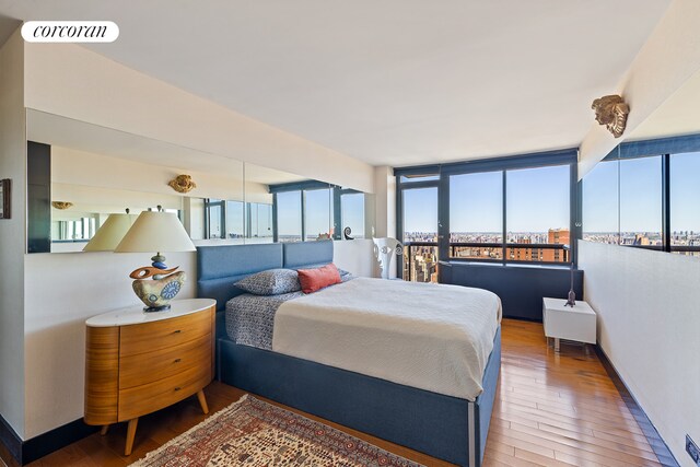 bedroom with multiple windows, hardwood / wood-style floors, and baseboards