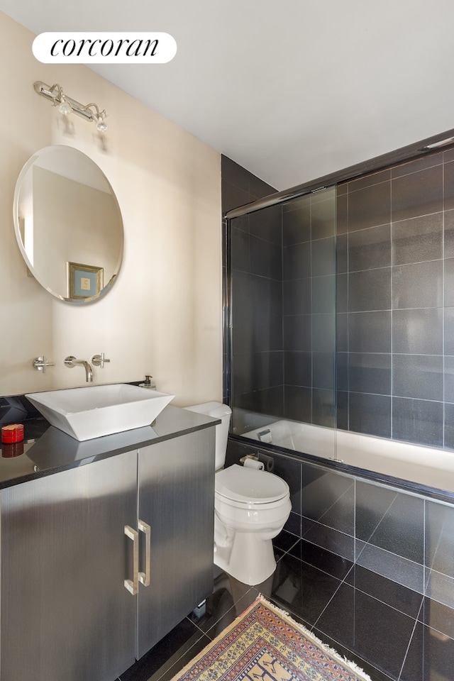 bathroom featuring toilet, vanity, tiled shower / bath, and tile patterned flooring