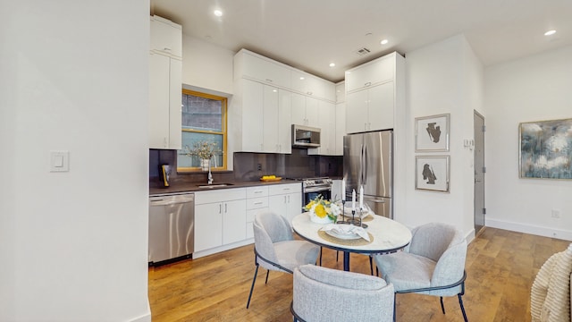 211 Jackson St Unit Garden2, New York City, NY 11211 - kitchen featuring stainless steel appliances, a sink, backsplash, light wood-style flooring, and dark countertops