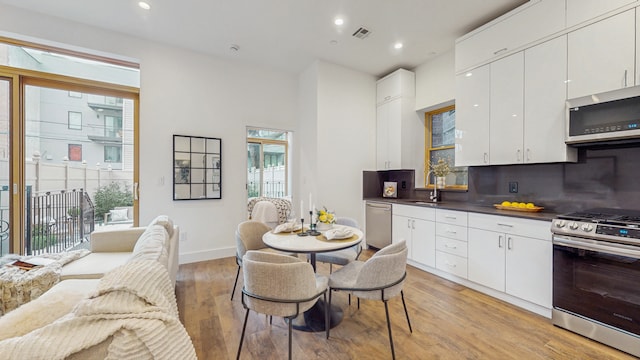 211 Jackson St Unit Garden2, New York City, NY 11211 - kitchen featuring stainless steel appliances, a sink, light wood-style floors, dark countertops, and white cabinets