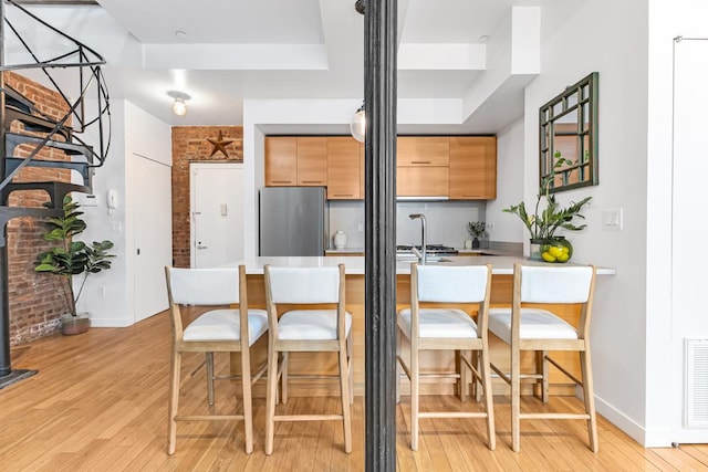 364 Manhattan Ave Unit 1-G, New York City, NY 11211 - kitchen with freestanding refrigerator, light wood-style flooring, a breakfast bar area, and a peninsula