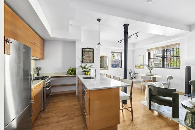 364 Manhattan Ave Unit 1-G, New York City, NY 11211 - kitchen with appliances with stainless steel finishes, a peninsula, a sink, brown cabinets, and a breakfast bar area