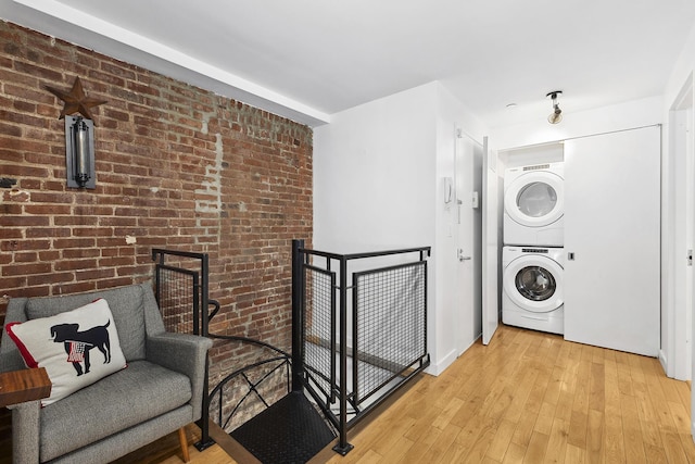 364 Manhattan Ave Unit 1-G, New York City, NY 11211 - laundry area with stacked washing machine and dryer, brick wall, and light wood-style flooring