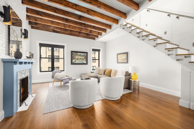 living area with stairs, beamed ceiling, wood finished floors, a premium fireplace, and baseboards