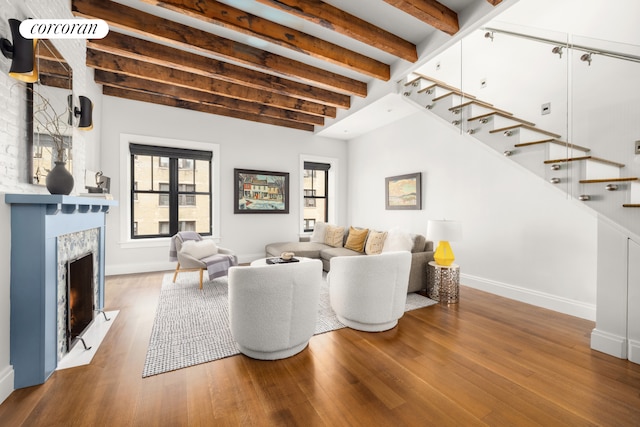 living area with beam ceiling, stairs, plenty of natural light, and a fireplace with flush hearth